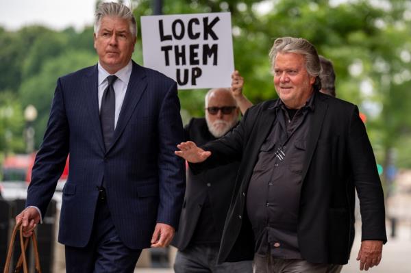 A man holds a sign that reads "Lock Them Up" as Attorney Matthew Evan Corcoran (L) and Steve Bannon, former advisor to President Do<em></em>nald Trump, depart federal court on June 6, 2024 in Washington, DC. 