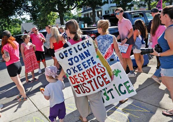A protester carrying as sign calling for Officer John O'Keefe to receive "justice" in the case.